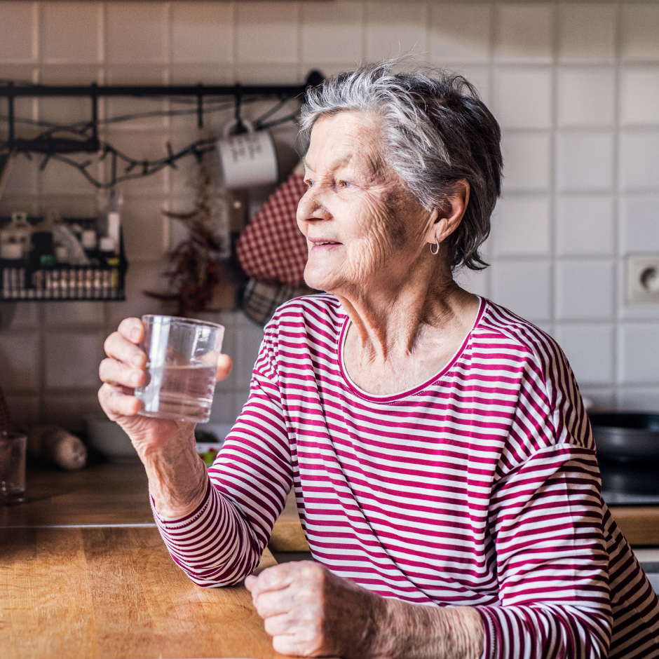 Foto de una mujer mayor sonriendo y sosteniendo un vaso de agua