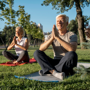 Foto de dos personas mayores haciendo yoga en un parque.